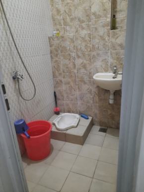 Kamar mandi dengan toilet duduk, wastafel, shower, dan ember